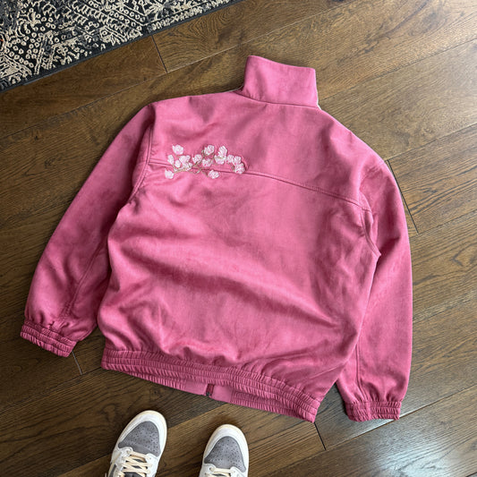 Pink sweatpants on a wooden floor with a person wearing gray sneakers.
