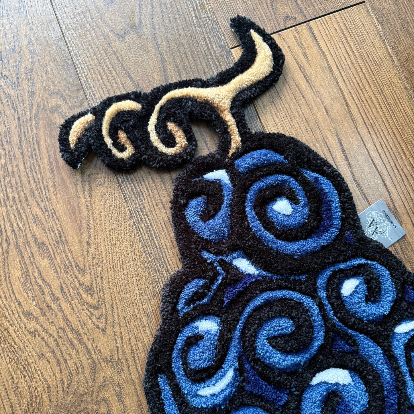 Decorative rug with blue and black spiral pattern on a wooden floor